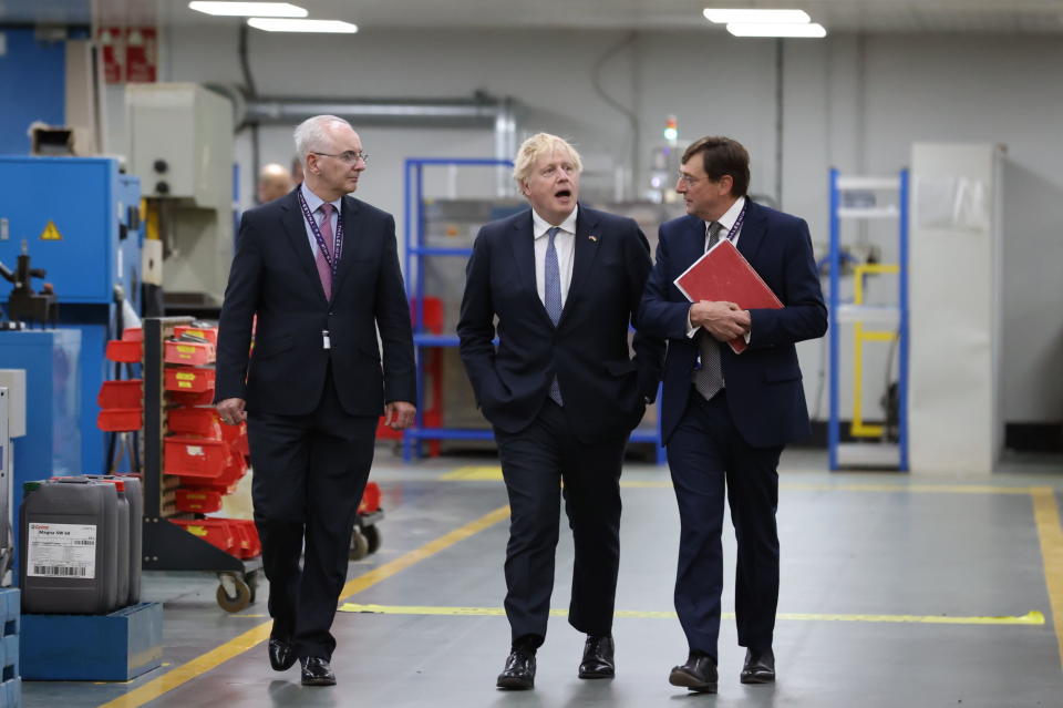 Britain's Prime Minister Boris Johnson with Alex Cresswell, CEO of Thales UK, right, and Philip McBride, Managing Director of Thales Belfast, on the factory floor at Thales weapons manufacturer in Belfast, Monday May 16, 2022, during a visit to Northern Ireland. Johnson said there would be “a necessity to act” if the EU doesn't agree to overhaul post-Brexit trade rules that he says are destabilizing Northern Ireland's delicate political balance. Johnson held private talks with the leaders of Northern Ireland's main political parties, urging them to get back to work. (Liam McBurney/Pool via AP)