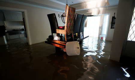 A family puts their belongings on their dining room table to keep them above floodwaters from Harvey in Houston, Texas August 31, 2017. REUTERS/Rick Wilking