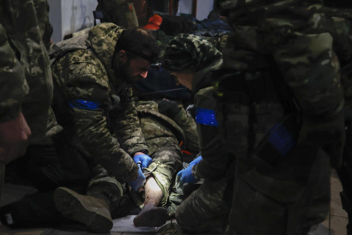 Ukrainian servicemen administer first aid to a wounded soldier in a shelter in Soledar, the site of heavy battles with Russian forces in the Donetsk region, Ukraine, Sunday, Jan. 8, 2023. (AP Photo/Roman Chop)