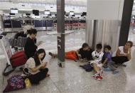 Passengers from South Korea (L), the Philippines (R) and Poland (4th R), whose flights to their home countries are cancelled in anticipation of typhoon Usagi, charge their tablet and smartphones at Hong Kong International Airport September 22, 2013. REUTERS/Bobby Yip