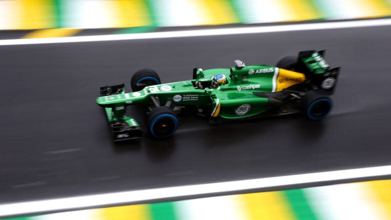 A photo of a green Caterham F1 car racing on track. 