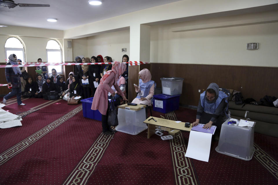 An Afghan woman center, registers to cast her votes during the Parliamentary elections in Kabul, Afghanistan, Saturday, Oct. 20, 2018. Tens of thousands of Afghan forces fanned out across the country as voting began Saturday in the elections that followed a campaign marred by relentless violence. (AP Photo/Rahmat Gul)