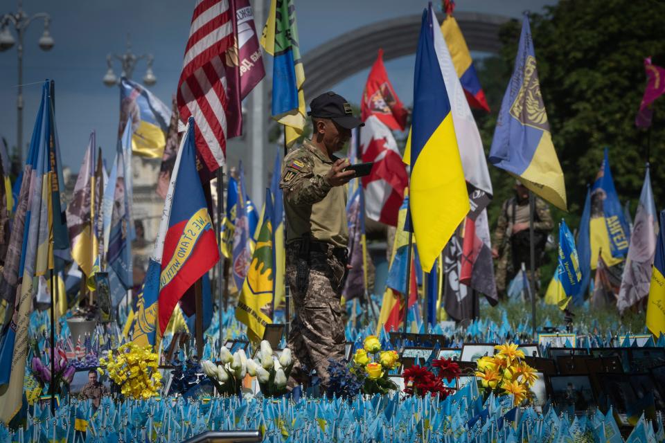 A Columbian volunteer soldier of Ukraine's International Legion makes a video at a makeshift memorial for fallen Ukrainian soldiers on Independence Square in Kyiv (AP)