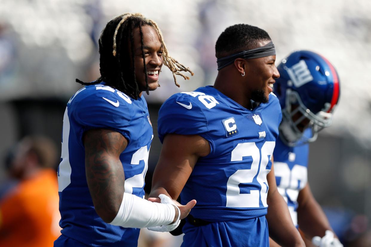 New York Giants safety Xavier McKinney (29) interacts with New York Giants running back Saquon Barkley (26) before an NFL football game against the Denver Broncos, Sunday, Sept. 12, 2021, in East Rutherford, N.J. The Denver Broncos won 27-13. (AP Photo/Steve Luciano)