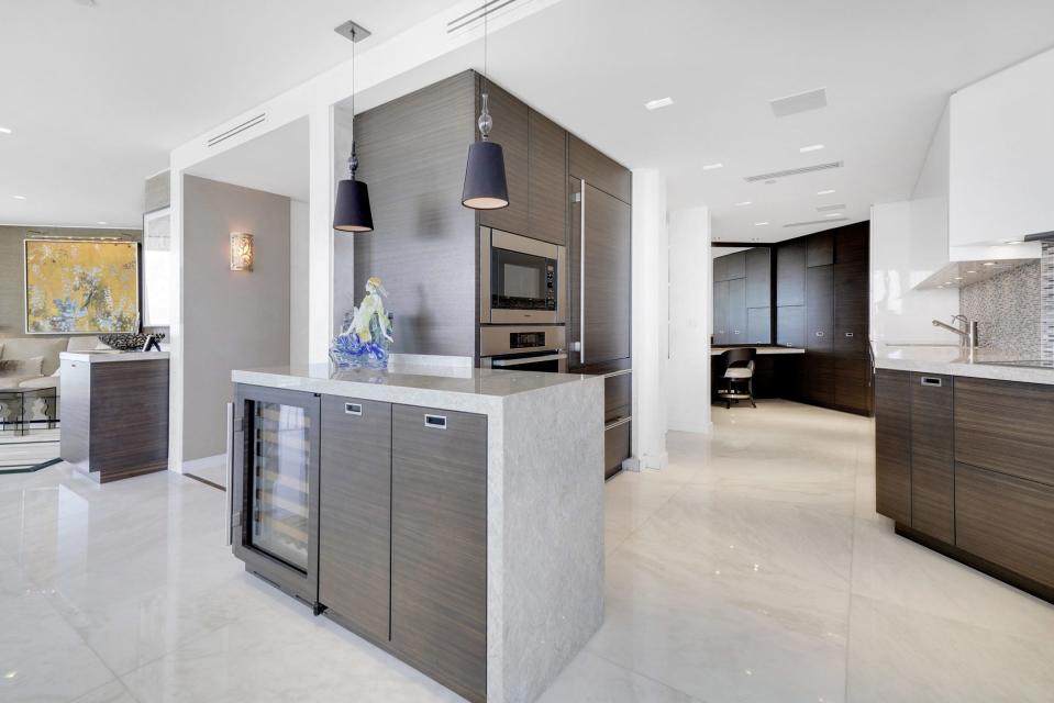 The sleek kitchen opens directly to the dining area. The den can be glimpsed at the rear left.