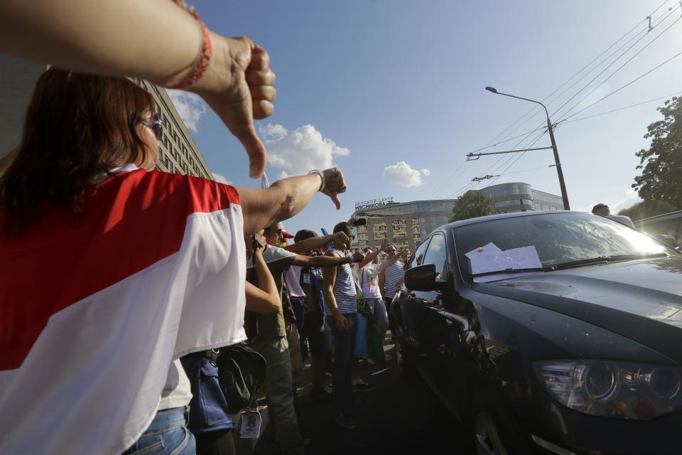 People gesture as they block a car carrying Uladzimir Karanik, Minister of Health of the Republic of Belarus during a rally in Minsk, Belarus, Monday, Aug. 17, 2020. Workers heckled and jeered President Alexander Lukashenko on Monday as he visited a factory and strikes grew across Belarus, raising the pressure on the authoritarian leader to step down after 26 years in power. (AP Photo/Sergei Grits)