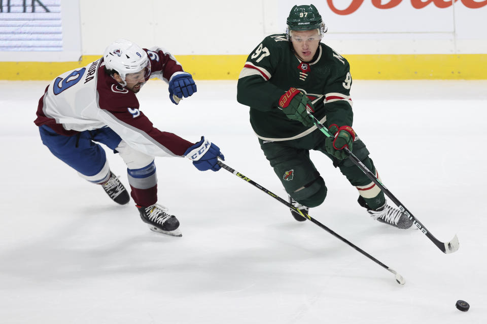 Minnesota Wild's Kirill Kaprizov (97) handles the puck against Colorado Avalanche's Dennis Gilbert (9) in the first period of a preseason NHL hockey game Monday, Oct. 4, 2021, in St. Paul, Minn. (AP Photo/Stacy Bengs)