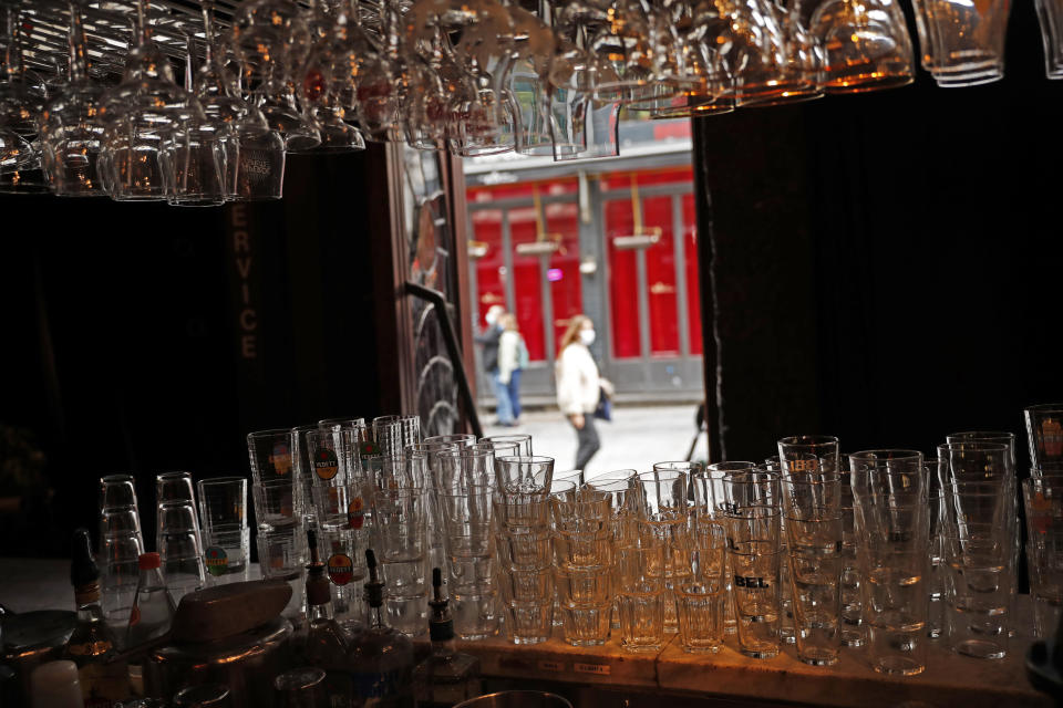 People walk past a closed bar in downtown Brussels, Thursday, Oct. 8, 2020. Since bars in Brussels were forced to close as of Thursday for at least a month to deal with a massive surge in Covid-19 cases while restaurants were allowed to remain open, the big question on the streets is: when is a bar a bar and when is a bar a restaurant. (AP Photo/Francisco Seco)