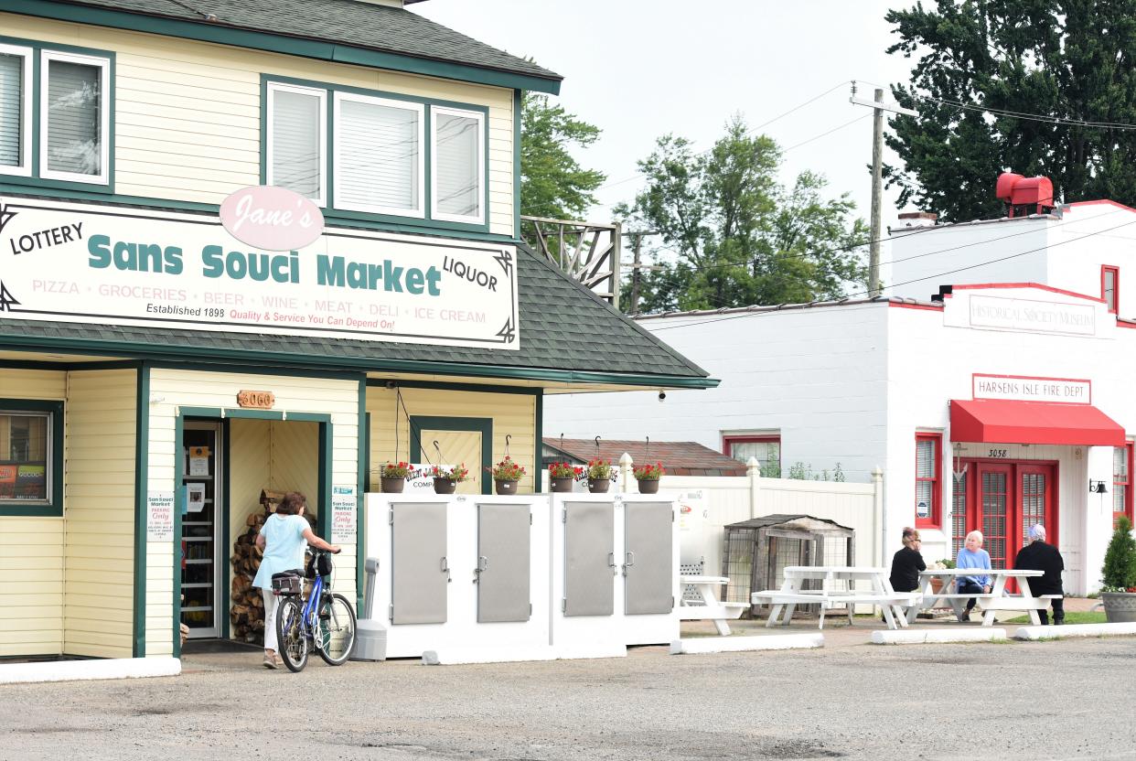 A bicyclist pulls up to Jane's Sans Souci Market, while others gather nearby on Tuesday, Aug. 1, 2023, in the Harsens Island town. The area along South Channel Drive is a focus for a new nonprofit formed to help revitalize Sans Souci.