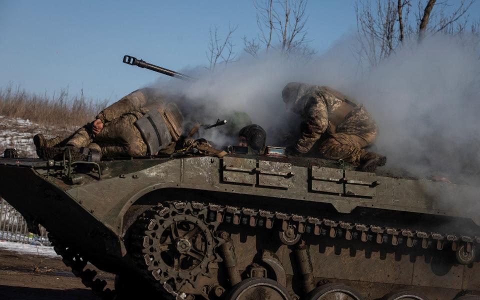 Ukrainian service members ride atop of a BMP-2 infantry fighting vehicle near a frontline in Donetsk - STRINGER