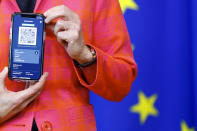 FILE - In this June 16, 2021, file photo, European Commission President Ursula von der Leyen shows a phone, as she gives a press statement on the new COVID-19 digital travel certificate at the European Commission headquarters in Brussels. In both the U.S. and the EU, officials are struggling with the same question: how to boost vaccination rates to the max and end a pandemic that has repeatedly thwarted efforts to control it. In the European Union, officials in many places are requiring people to show proof of vaccination, a negative test or recent recovery from COVID-19 to participate in everyday activities — even sometimes to go to work. (Johanna Geron/Pool Photo via AP, File)