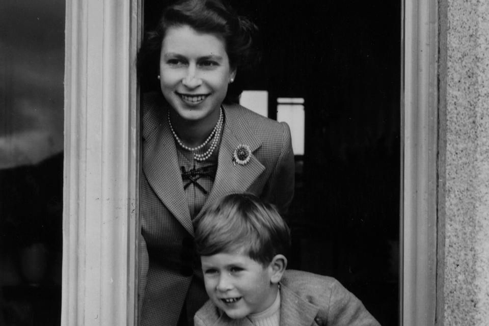 28th September 1952: Queen Elizabeth II and her son Charles leaning out of a window at Balmoral Castle