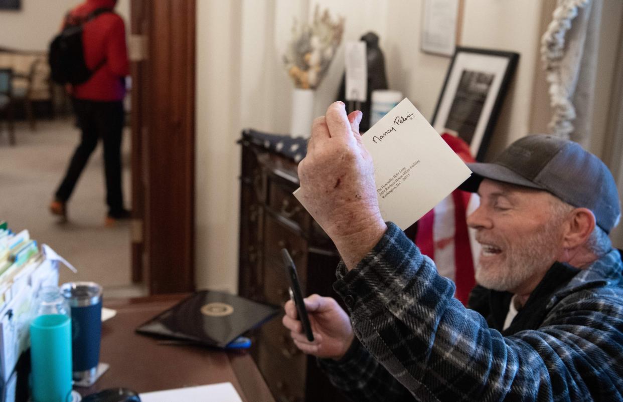 A pro-Trump rioter goes through items on the desk of a Pelosi staffer. (Photo: SAUL LOEB via Getty Images)