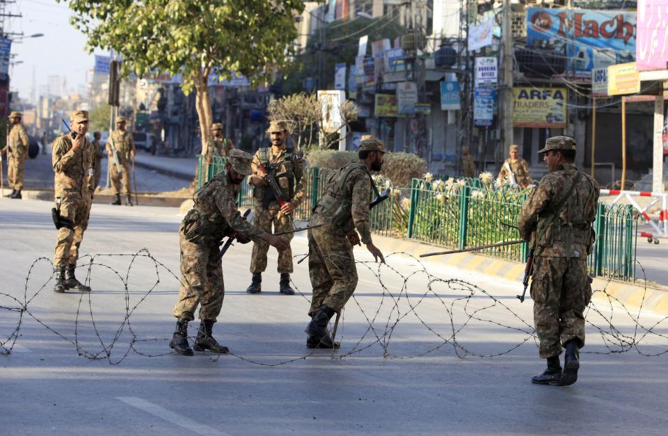 Pakistani army soldiers place barbwire to secure a street during a curfew in Rawalpindi