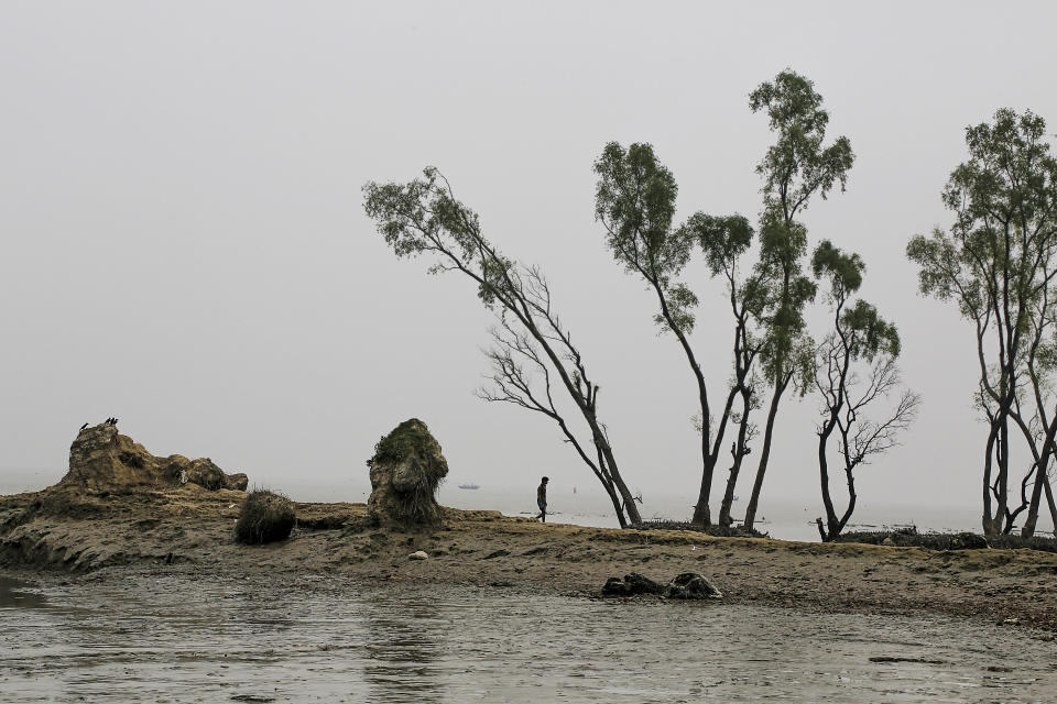 In this Nov. 17, 2015 file photo, Ali walks past a stretch of land where his home once stood, in the island district of Bhola, where the Meghna River spills into the Bay of Bengal, Bangladesh. Bangladesh plans to present its “climate prosperity plan” aimed at mitigating the effects of global warming on economic development at the forthcoming U.N. climate talks in Glasgow, Bangladeshi climate officer Abul Kalam Azad said in an interview with The Associated Press on Friday, Oct. 22, 2021. With most of its 160 million people tightly packed into low-lying areas along the Bay of Bengal, Bangladesh is considered especially prone to flooding, extreme weather and the loss of farmland to rising ocean levels. (AP Photo/Shahria Sharmin, File)