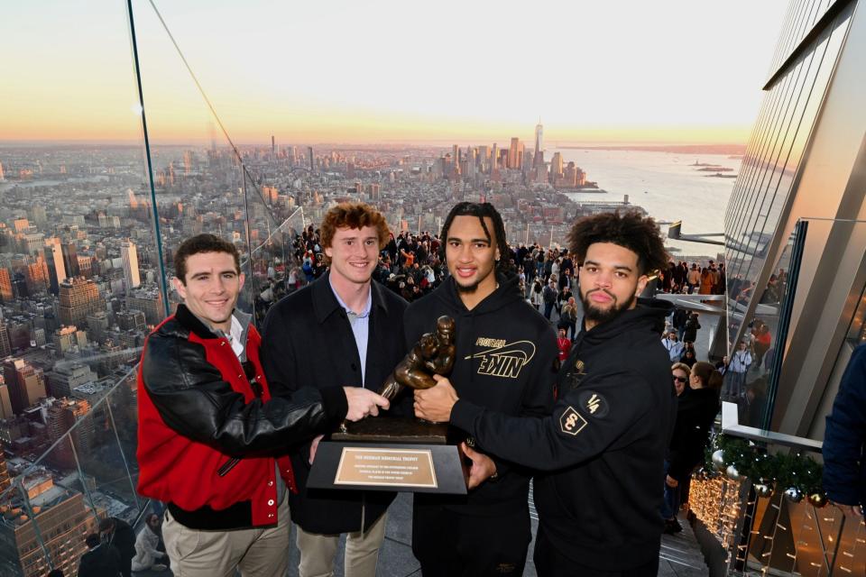 Georgia quarterback Stetson Bennett, TCU quarterback Max Duggan, Ohio State quarterback C.J. Stroud and Southern Cal quarterback Caleb Williams  pose with the Heisman Trophy at The Edge observation deck in New York City.