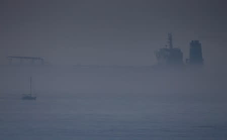 Sailboat sails past Iranian oil tanker Grace 1 as it sits anchored in the fog after it was seized in July by British Royal Marines in the Strait of Gibraltar