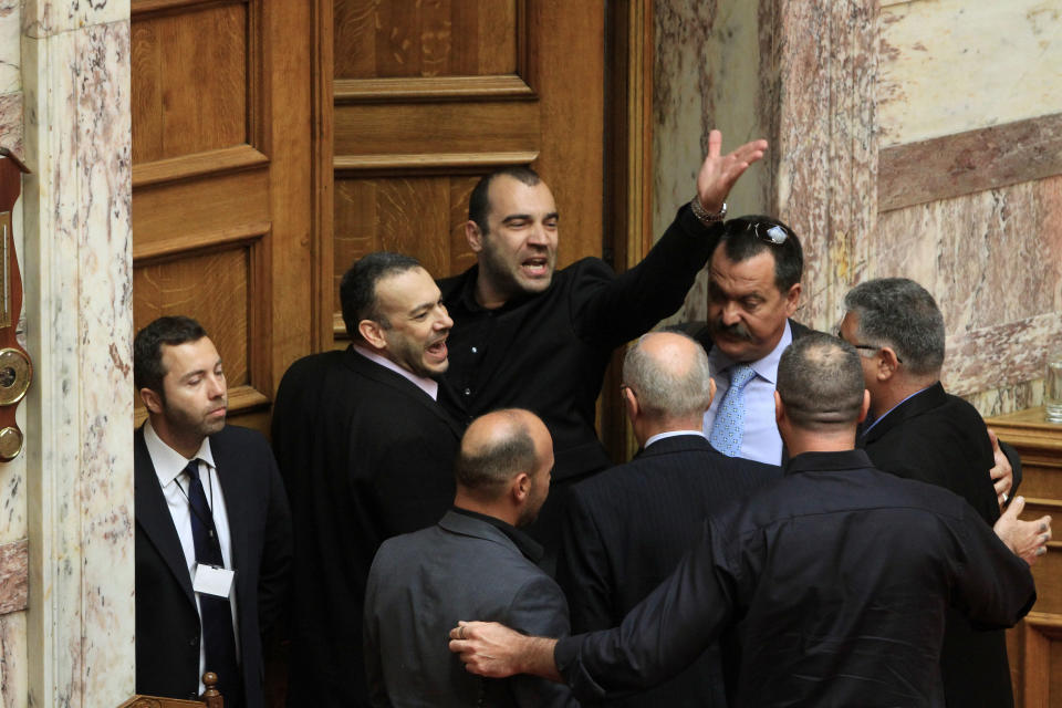 Panagiotis Iliopoulos, a deputy for the far-right Golden Dawn party, centre top, gestures as he shouts insults at other lawmakers with his colleague in the same party at the Greek Parliament in Athens, Friday, May 17, 2013. (AP Photo/Fosphotos, Panayiotis Tzamaros)