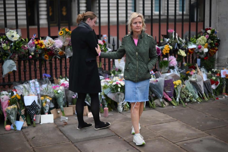 A person reacts near floral tributes placed at Buckingham Palace, following the passing of Queen Elizabeth, in London (AFP via Getty Images)
