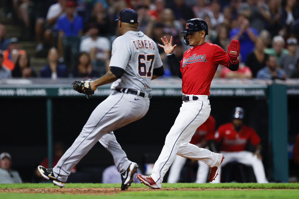 Cleveland Guardians' Andres Gimenez, right, scores past Detroit Tigers relief pitcher Jose Cisnero on a passed ball by catcher Eric Haase during the sixth inning of a baseball game Wednesday, Aug. 17, 2022, in Cleveland. (AP Photo/Ron Schwane)