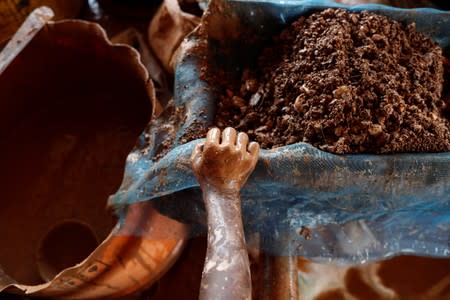 An informal gold miner carries gold-laden gravel after it was ground up by a rock breaking machine for further processing at a site in Nsuaem-Top