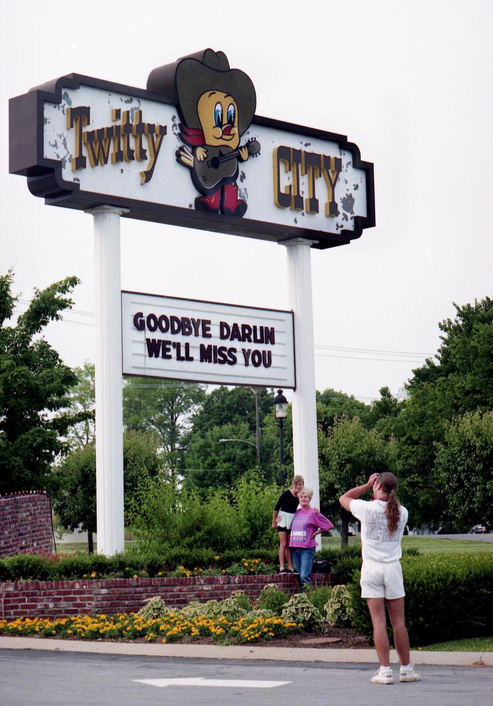 A Conway Twitty fan takes a picture of two other fans in front of the Twitty City sign in Hendersonville, Tenn., June 6, 1993, with the messages "Goodbye Darlin, We'll Miss You," two days after the Hall of Famer Twitty died of an abdominal aneurysm in Springfield, Mo.