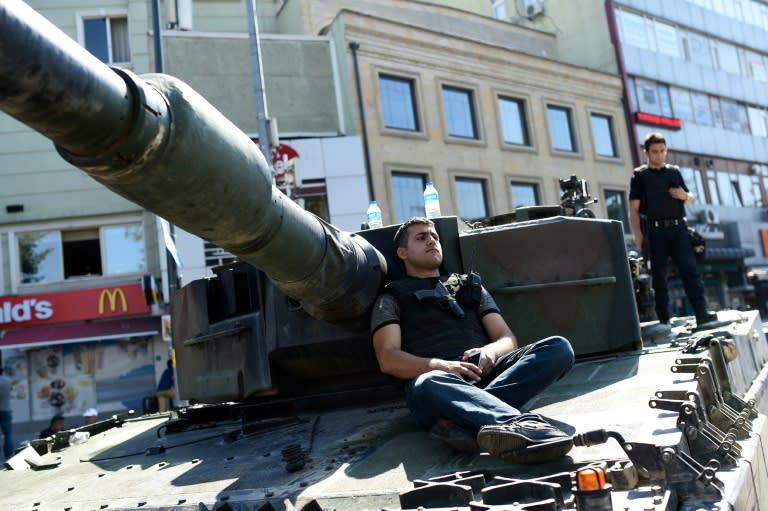 Turkish police officers sit on a tank in Istanbul on July 16, 2016