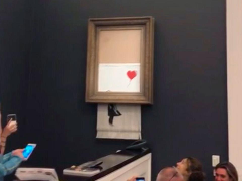 A Banksy artwork self-destructing after being sold at auction for $1.4 million.