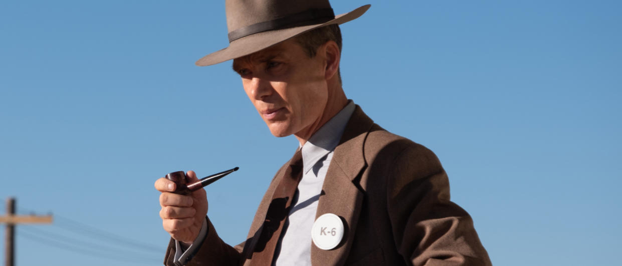  Cillian Murphy stands against a blue sky, holding a pipe, in Oppenheimer. 