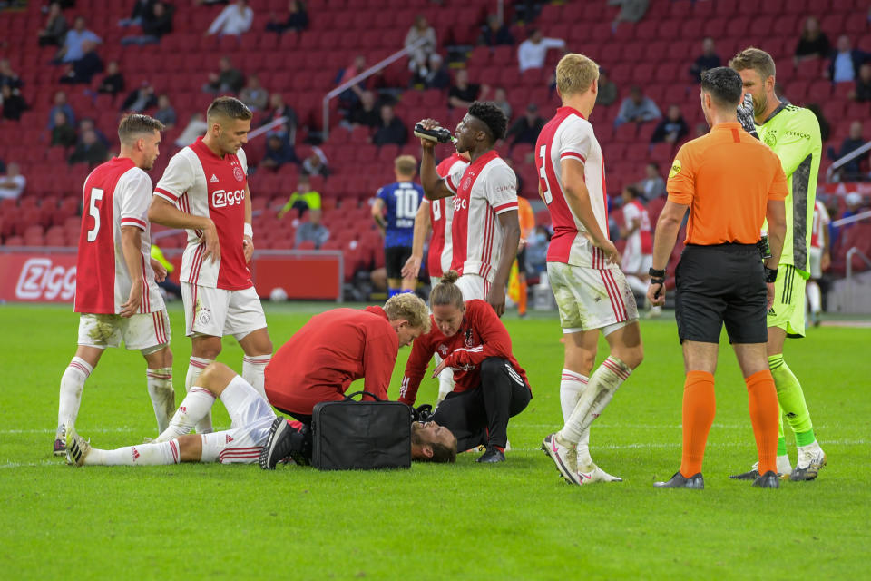 Médicos del Ajax atendiendo a Daley Blind mientras otros jugadores y árbitros observan.