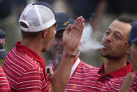 Xander Schauffele blows smoke toward Jordan Spieth after the USA team defeated the International team in a singles match at the Presidents Cup golf tournament at the Quail Hollow Club, Sunday, Sept. 25, 2022, in Charlotte, N.C. (AP Photo/Chris Carlson)