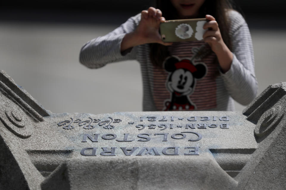 A child photographs part of the pedestal of the toppled statue of Edward Colston in Bristol, England, Monday, June 8, 2020, following the downing of the statue on Sunday at a Black Lives Matter demo. The toppling of the statue was greeted with joyous scenes, recognition of the fact that he was a notorious slave trader — a badge of shame in what is one of Britain’s most liberal cities. (AP Photo/Kirsty Wigglesworth)