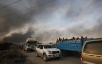 People stand at a back of a truck as they flee Ras al Ain town