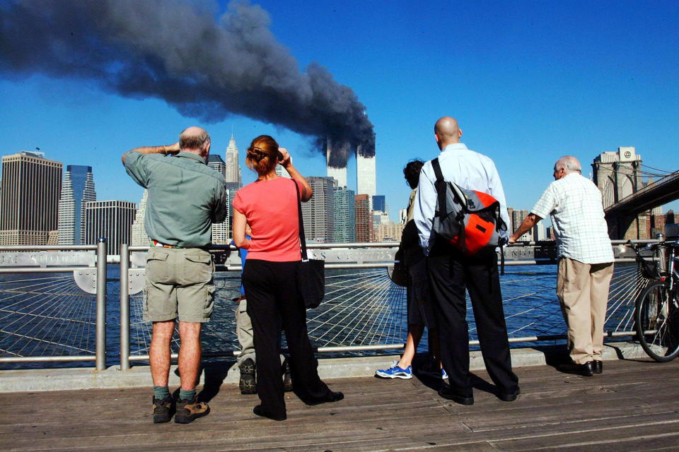 <p>Pedestrians on the waterfront in Brooklyn look across the East River to the burning World Trade Center towers on Sept. 11, 2001. (Photo: Henny Ray Abrams/AFP/Getty Images) </p>