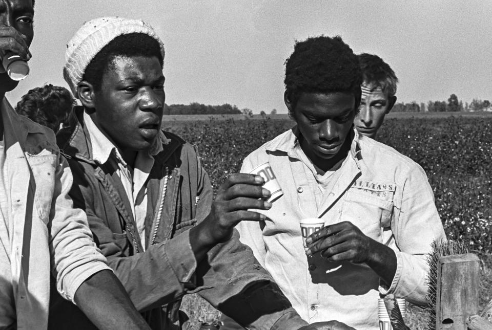 This 1975 photo shows prisoners at the Arkansas Department of Corrections Cummins Unit taking a water break while on work detail picking cotton in Grady, Ark. As daily temperatures hit record highs across much of the South, a federal judge has taken an unusual step, challenging the treatment of mostly Black incarcerated workers in the fields. (Bruce Jackson via AP)