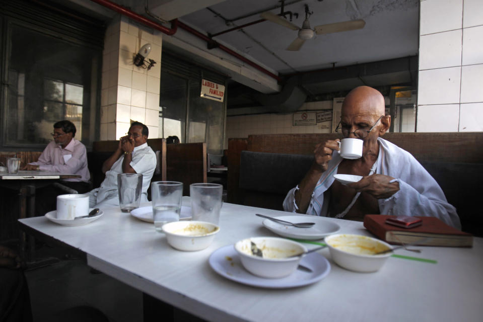 Mahesh Chaturvedi, who dresses up like Mahatma Gandhi, drinks coffee in New Delhi