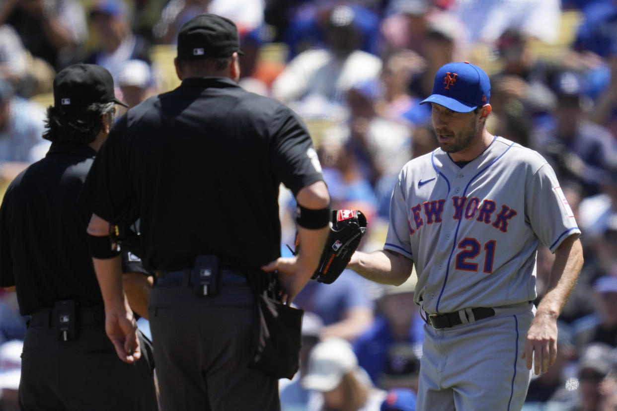 New York Mets starting pitcher Max Scherzer (21) has hit glove inspected by umpire Phil Cuzzi, left, and umpire Dan Bellino during the third inning of a baseball game against the Los Angeles Dodgers in Los Angeles, Wednesday, April 19, 2023. (AP Photo/Ashley Landis)