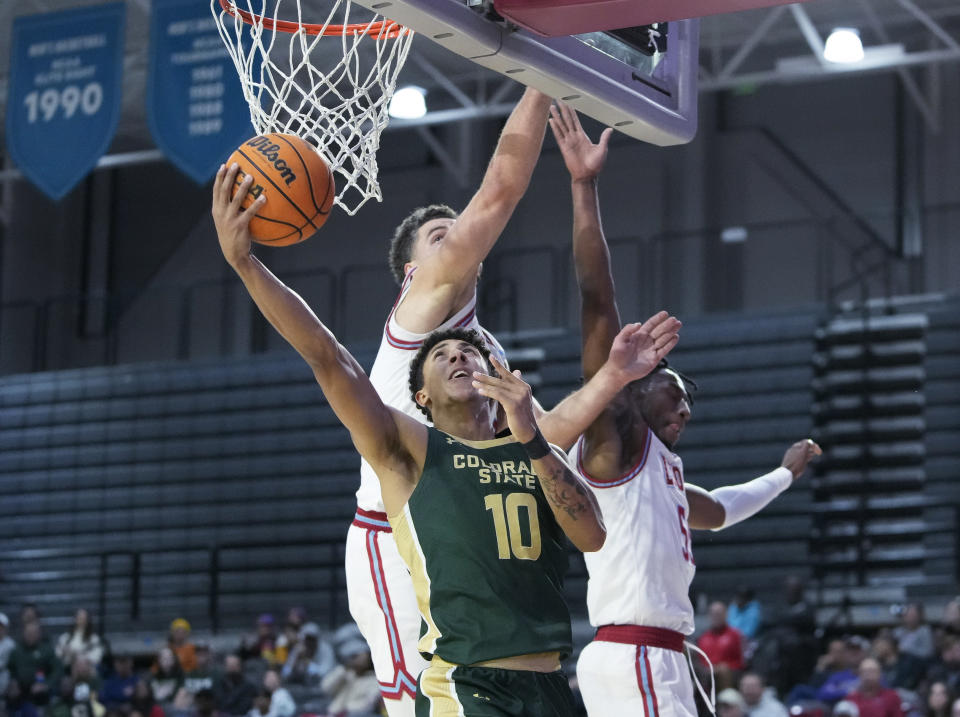 Colorado State guard Nique Clifford, front, shoots past Loyola Marymount forward Alex Merkviladze, left, and guard Dominick Harris during the first half of an NCAA college basketball game Friday, Dec. 22, 2023, in Los Angeles. (AP Photo/Ryan Sun)