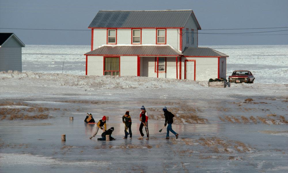 Children play ice hockey along shoreline of Saint Lawrence River.