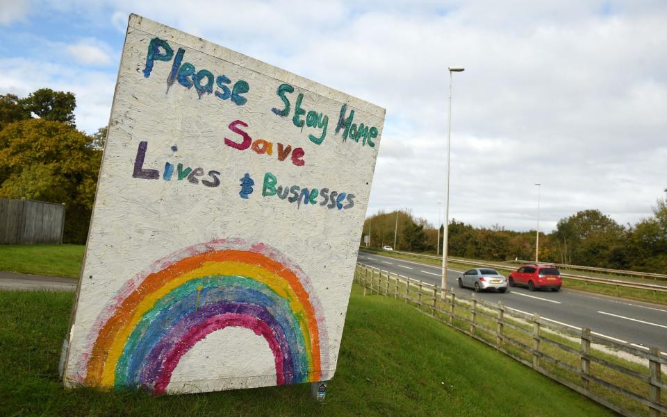 A sign by the side of a road in Flint, north Wales, urges people to stay at home during the country's new 'fire break' lockdown - Oli Scarff/AFP