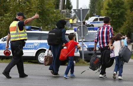A German policeman directs migrants towards a registration point after crossing the border from Austria in Freilassing, Germany September 17, 2015. REUTERS/Michaela Rehle