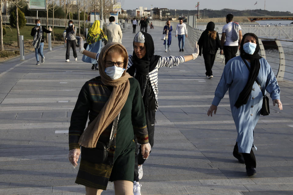 People wearing face masks exercise on the shore of an artificial lake, in Western Tehran, Iran, Sunday, March 15, 2020. Many people in Tehran shrugged off warnings over the new coronavirus as authorities complained that most people in the capital are not treating the crisis seriously enough. For most people, the new coronavirus causes only mild or moderate symptoms. For some it can cause more severe illness. (AP Photo/Vahid Salemi)