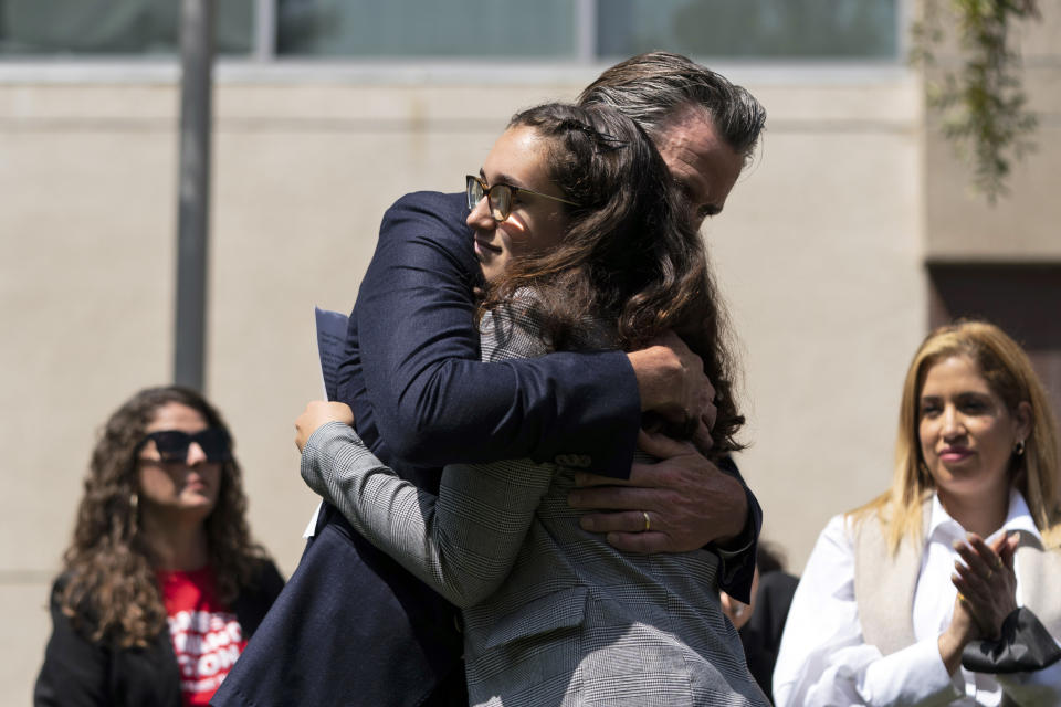 California Gov. Gavin Newsom hugs gun violence survivor, Mia Tretta, 17, after he was introduced by her at a news conference in Santa Monica, Calif., Friday, July 22, 2022.. Newsom signed a gun control law Friday, a month after conservative justices overturned women's constitutional right to abortions and undermined gun control laws in states including California. (AP Photo/Jae C. Hong)