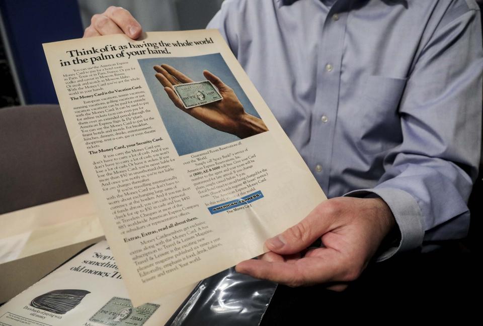 HOLD FOR STORY BY KEN SWEETS--Ira Galtman, American Express director of corporate archives, shows a 1970s magazine page with the original American Express "Green Card," Wednesday Wednesday, Oct. 23, 2019, in New York. For 50 years the "Green Card" was everywhere and has been revamped, with a new look and more travel benefits. (AP Photo/Bebeto Matthews)