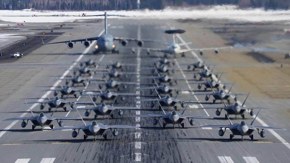A picture of a so-called "elephant walk" readiness exercise at Joint Base Elmendorf-Richardson showing 24 of 3rd Wing's F-22s, as well as a C-17 and an E-3. <em>USAF</em>