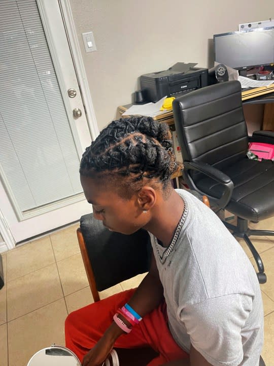 In this photo provided by Darresha George, her son Darryl George, 17, a junior at Barbers Hill High School in Mont Belvieu, Texas, sits for a photo showing his locs, at the family’s home, Sept. 10, 2023. The same week a state law went into effect prohibiting discrimination on the basis of hair, George was suspended because his locs did not comply with the district’s dress code. (Darresha George via AP)