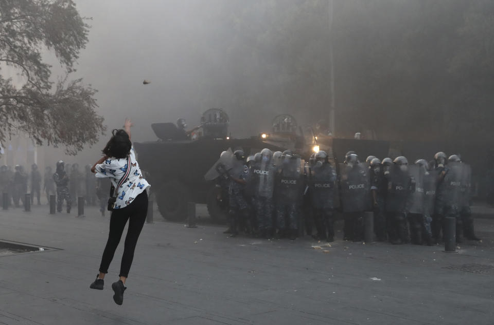 ARCHIVO- Una manifestante lanza una piedra contra agentes de la policía durante una protestas cerca del Parlamento, en Beirut, Líbano, el martes 1 de septiembre de 2020. (AP Foto/Bilal Hussein, Archivo)