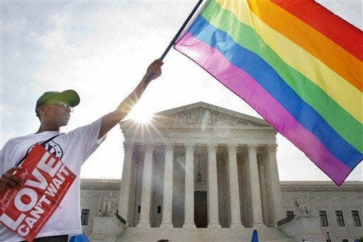 Carlos McKnight of Washington waves a flag in support of gay marriage outside of the Supreme Court in June 2015. Civil rights activists fear the court has threatened LGBT rights by overturning Roe v. Wade.