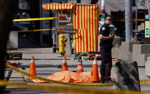 A police officer stands next to a victim of the Toronto attack - Credit: Reuters