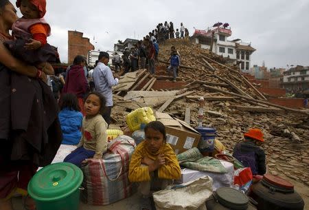 People sit with their belongings outside a damaged temple in Bashantapur Durbar Square after a major earthquake hit Kathmandu, Nepal April 25, 2015. REUTERS/Navesh Chitrakar